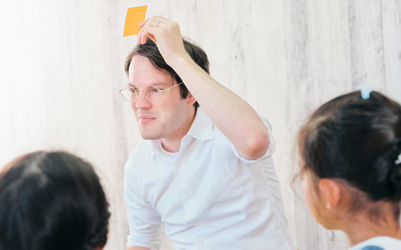 外国人講師がカードを使って子どもに英語を教える様子