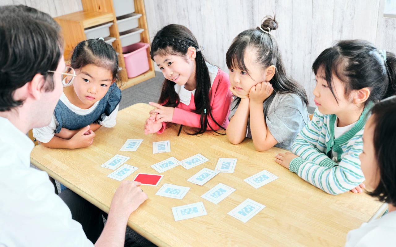 英語カードゲームを楽しむ子どもたちと外国人講師のレッスン風景
